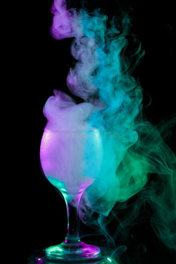 Abstract art. Hookah blue - green - violet smoke into cocktail glass on a white background. Witch potion background for Halloween. Unusual bar drink. Drink in the glass with the effect of dry ice. Abstract art. Hookah blue - green - violet smoke into cocktail glass on a white background. Witch potion background for Halloween. Unusual bar drink. Drink in the glass with the effect of dry ice.