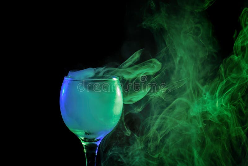 Abstract art. Hookah blue - green smoke in a cocktail glass on a white background. Witch potion background for Halloween. Unusual bar drink. Drink in the glass with the effect of dry ice. Abstract art. Hookah blue - green smoke in a cocktail glass on a white background. Witch potion background for Halloween. Unusual bar drink. Drink in the glass with the effect of dry ice.