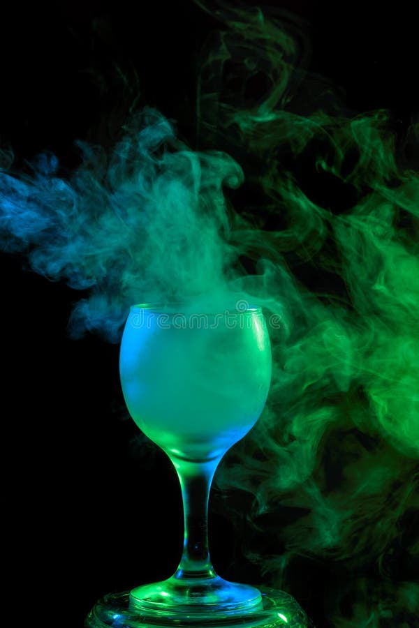 Abstract art. Hookah blue - green smoke in a cocktail glass on a white background. Witch potion background for Halloween. Unusual bar drink. Drink in the glass with the effect of dry ice. Abstract art. Hookah blue - green smoke in a cocktail glass on a white background. Witch potion background for Halloween. Unusual bar drink. Drink in the glass with the effect of dry ice.