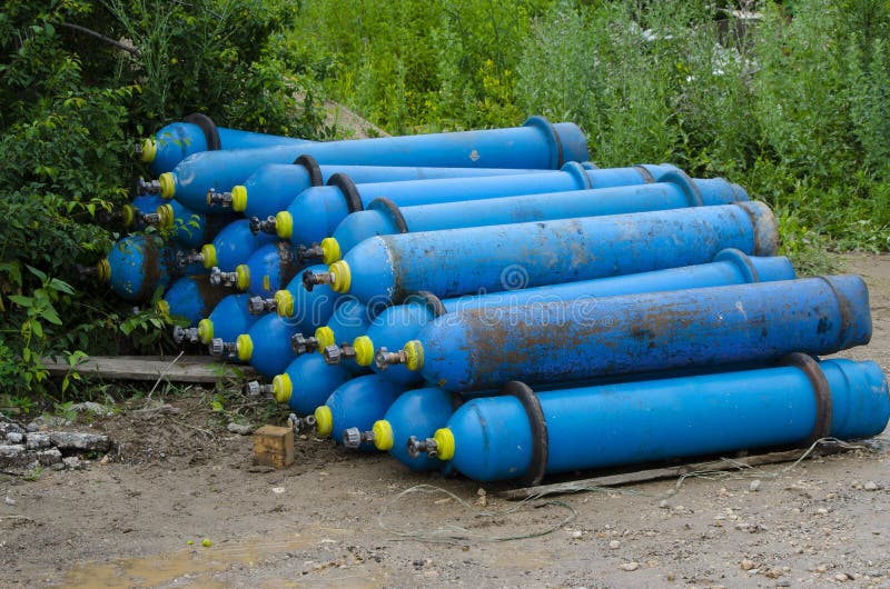 Blue industrial oxygen cylinders on the ground in the mud Unsafe storage of industrial waste royalty free stock photo Blue industrial oxygen cylinders on the ground in the mud Unsafe storage of industrial waste royalty free stock photo