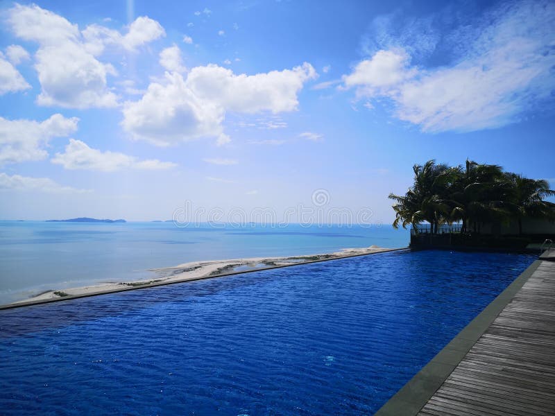 Infinity pool and ocean with blue sky and white clouds. Blue infinity pool water and ocean with blue sky and white clouds stock photos Infinity pool and ocean with blue sky and white clouds. Blue infinity pool water and ocean with blue sky and white clouds stock photos
