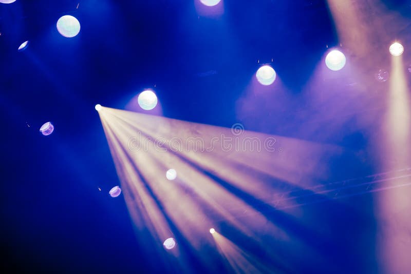 Blue light rays from the spotlight through the smoke at the theater or concert hall. Lighting equipment for a performance or show