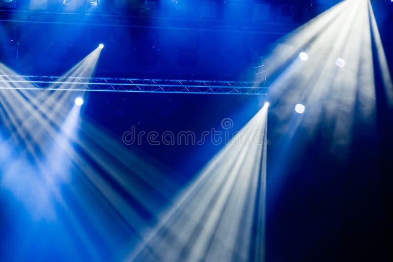 Blue light rays from the spotlight through the smoke at the theater or concert hall. Lighting equipment for a performance or show