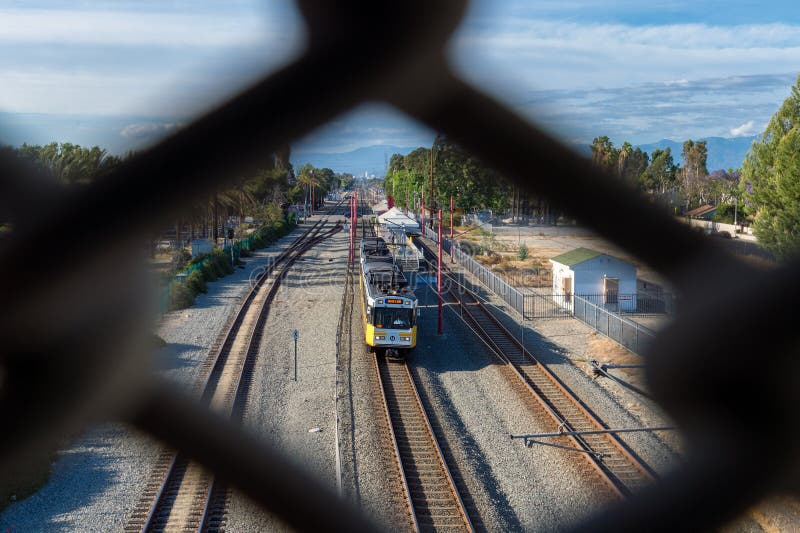 A southbound Blue Line light rail train travels through Watts in South Los Angeles. Downtown Los Angeles and the San Gabriel Mountains can be seen in the distance. Photo was taken from one of the chainlink pedestrian overpasses that cross the tracks. A southbound Blue Line light rail train travels through Watts in South Los Angeles. Downtown Los Angeles and the San Gabriel Mountains can be seen in the distance. Photo was taken from one of the chainlink pedestrian overpasses that cross the tracks.