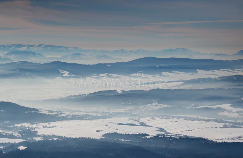Modré horské hřebeny a sněhová pole v mlžných údolích na Slovensku