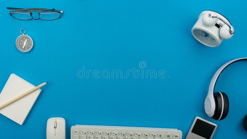 Blue office desk table with computer,wireless earphone,alarm clock and business objects, Top view with copy space for your text