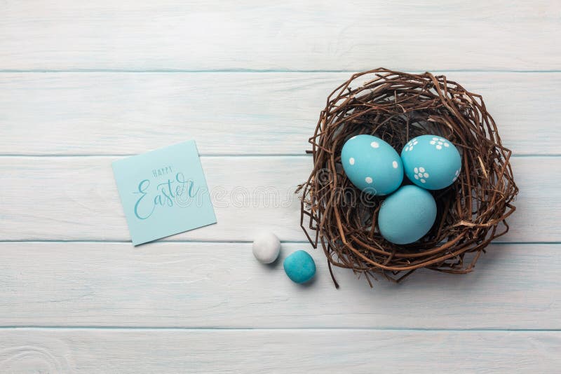 Blue painted eggs in nest and willow. Easter greeting card. Top view with space for your greetings