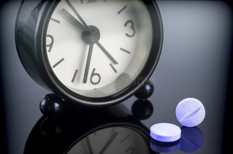 Blue pills next to a clock