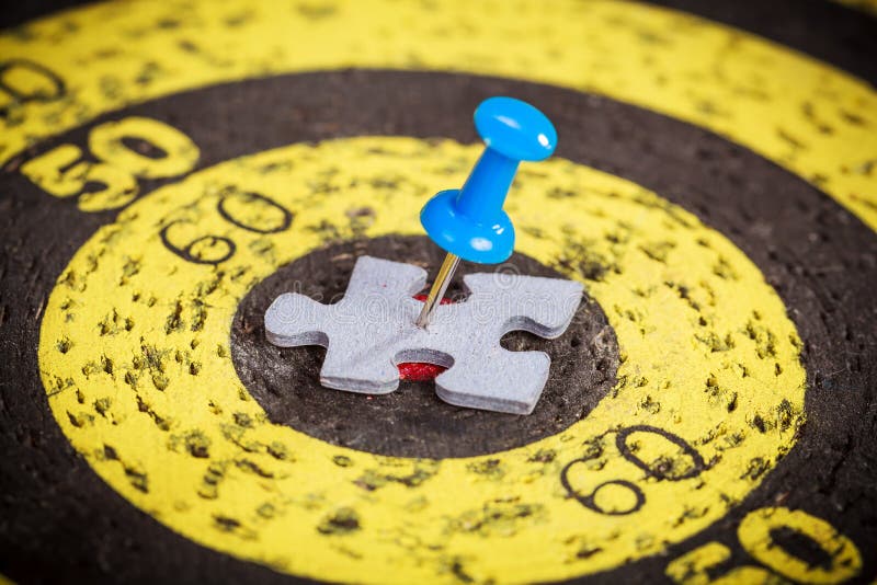 Blue pin stuck to man shape jigsaw puzzle piece on old target board stock images Blue pin stuck to man shape jigsaw puzzle piece on old target board stock images