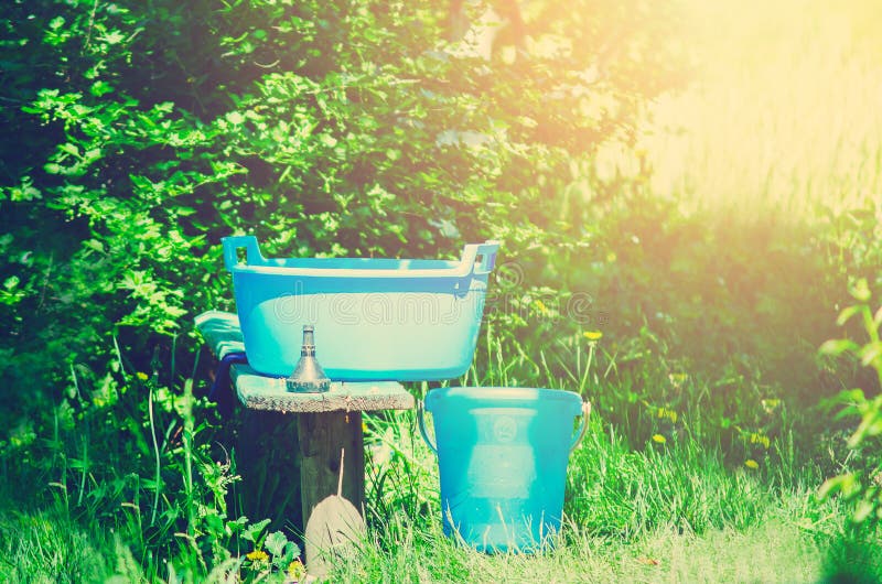 A blue plastic bucket and trough stand on the street. Housekeeping in a country house. Russia stock photo A blue plastic bucket and trough stand on the street. Housekeeping in a country house. Russia stock photo