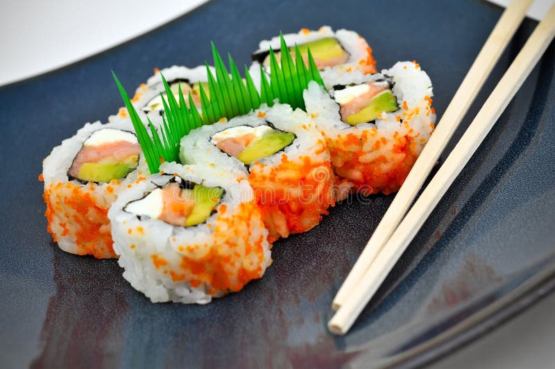 Sushi Philly rolls on a square blue plate with chopsticks. Some fancy grass garnish in the middle. The rolls contain salmon, avocado, cream cheese, and rice. Eaten with ginger and wasabi. Weight watchers stock images, royalty-free photos and pictures