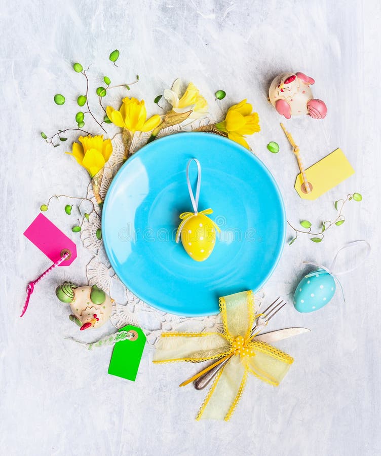 Blue plate with yellow easter egg, holiday decor and daffodil flowers on wooden background