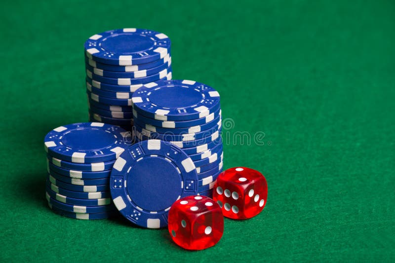 Blue poker chips and red cubes on the green table royalty free stock photography Blue poker chips and red cubes on the green table royalty free stock photography