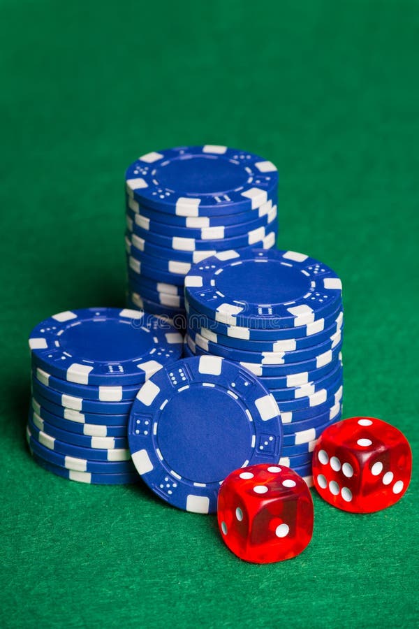 Blue poker chips and two cubes on the green table