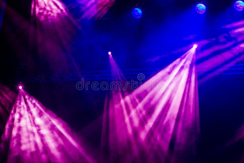 Blue and purple rays from the spotlight through the smoke at the theater or concert hall. Lighting equipment