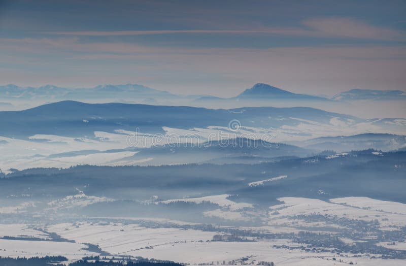 Blue ridges, misty snowy valleys and a conical peak in Slovakia
