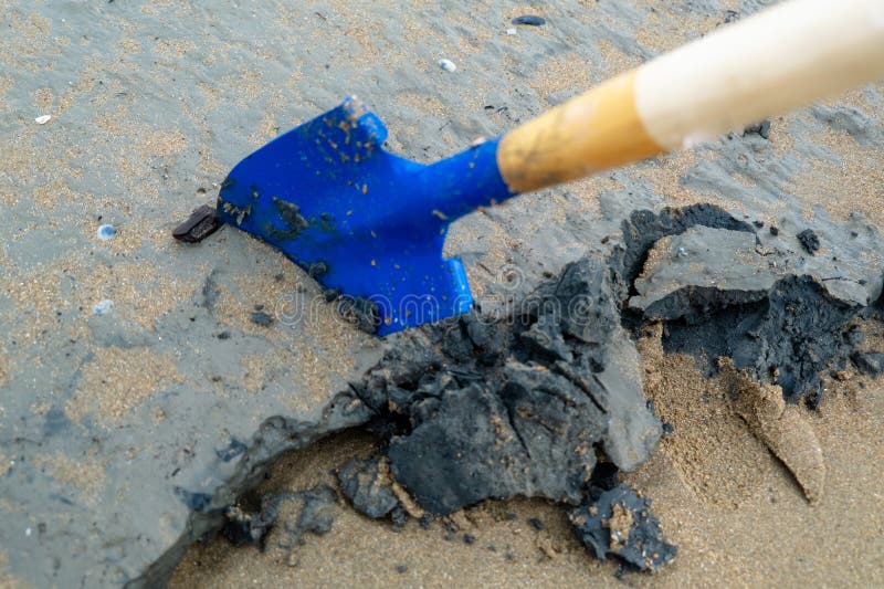 Blue shovel digging into wet sand and clay on beach stock photography
