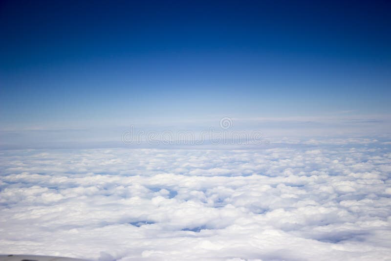 A view from the airplane, above white endless clouds, blue sky