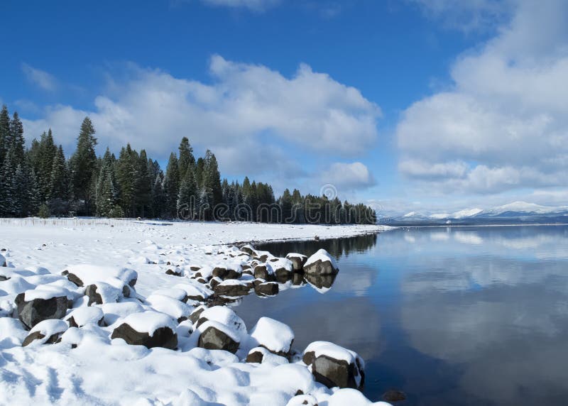 Blue sky over snowy winter mountain lake scene