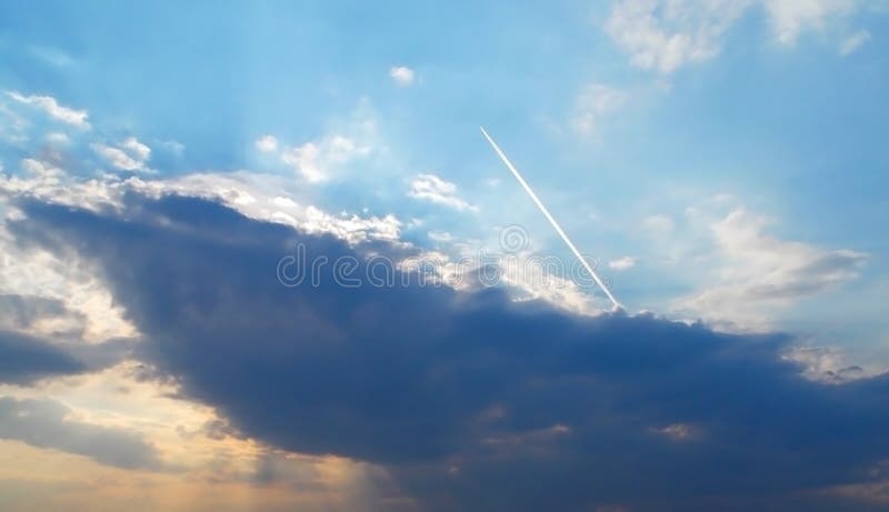 A Blue Sky with a Plane Trace. Dark Cloud and a Ray of Sunshine Behind ...