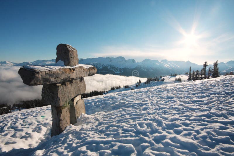 An inukshuk and a sun flare over Whistler and Blackcomb mountains, British Columbia, Canada. An inukshuk and a sun flare over Whistler and Blackcomb mountains, British Columbia, Canada.