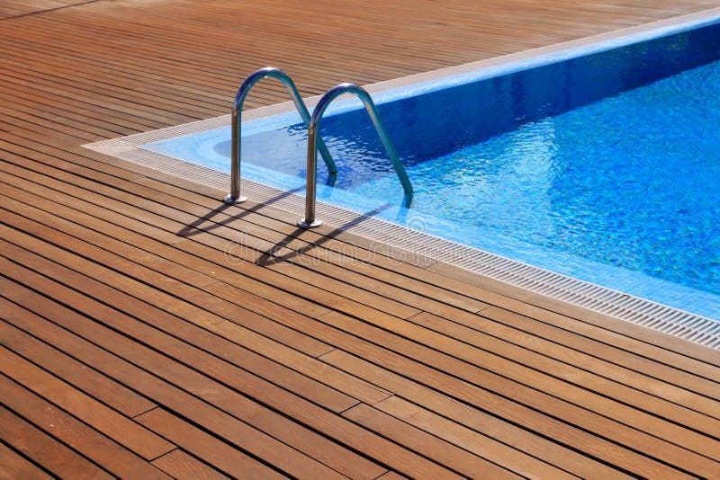 Blue swimming pool with teak wood flooring royalty free stock images