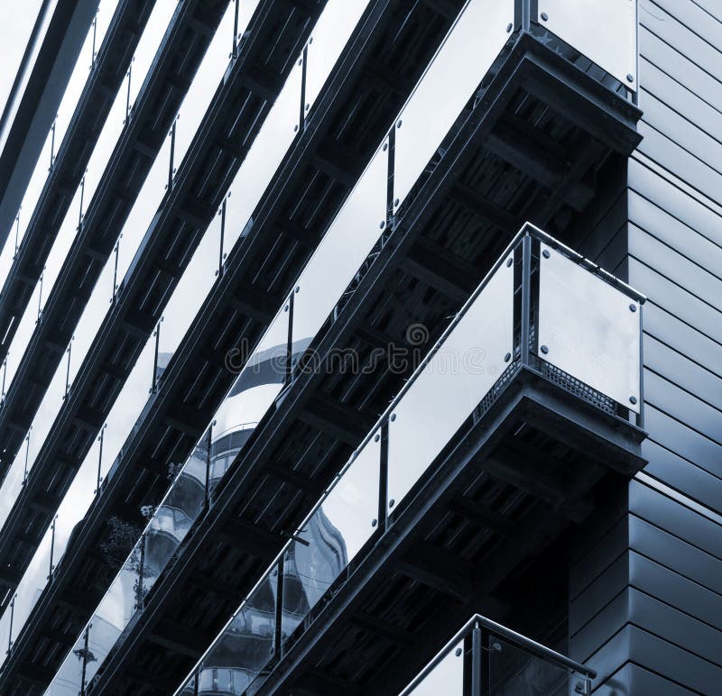 Blue toned corner view of modern apartments with stylish glass paneled balconies reflect nearby urban buildings. A blue toned corner view of modern apartments royalty free stock image Blue toned corner view of modern apartments with stylish glass paneled balconies reflect nearby urban buildings. A blue toned corner view of modern apartments royalty free stock image