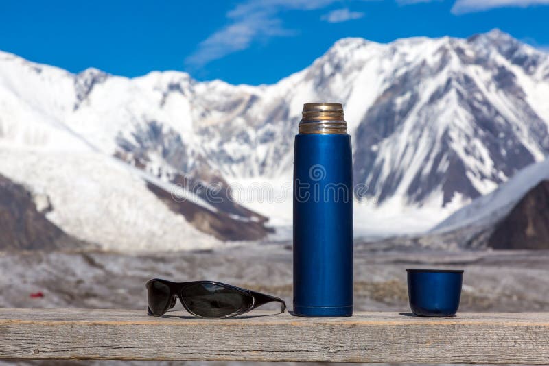 https://thumbs.dreamstime.com/b/blue-travel-thermos-opened-cup-sunglasses-wooden-table-high-mountains-background-majestic-himalaya-mountain-range-70071964.jpg