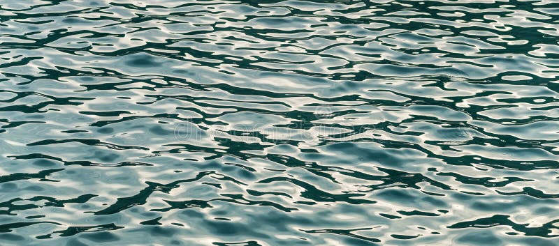 Blue water texture, with ripples and sun reflections