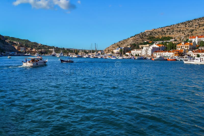 blue water with waves in bay of mountain town of Balaklava with marinas, white ships, boats and bright buildings, ripples