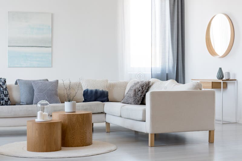 Blue and white painting and mirror in wooden frame in elegant living room interior with corner sofa and coffee table