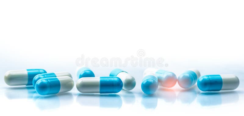 Blue and white capsules pill spread on white background with shadow and copy space. Global healthcare concept. Antibiotics drug stock photos Blue and white capsules pill spread on white background with shadow and copy space. Global healthcare concept. Antibiotics drug stock photos
