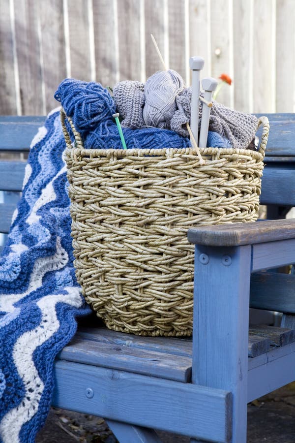 Blue wool and knitting needles in a wicker basket