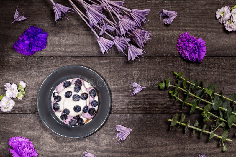 Blueberry Graham Cheesecake topped with fresh berries, on a dark wood background with purple flowers and twigs. Flat lay, top view royalty free stock photography Blueberry Graham Cheesecake topped with fresh berries, on a dark wood background with purple flowers and twigs. Flat lay, top view royalty free stock photography