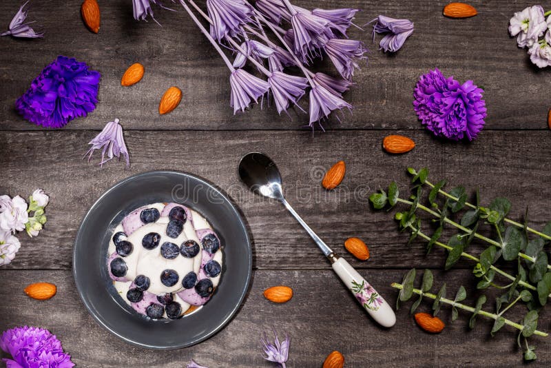 Blueberry Graham Cheesecake topped with fresh berries with a spoon on a dark wood background with almonds, purple flowers. stock image Blueberry Graham Cheesecake topped with fresh berries with a spoon on a dark wood background with almonds, purple flowers. stock image