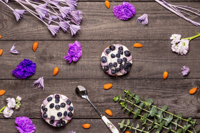 Blueberry Graham Cheesecakes topped with fresh berries with a spoon on a dark wood background with almonds, purple flowers stock images Blueberry Graham Cheesecakes topped with fresh berries with a spoon on a dark wood background with almonds, purple flowers stock images