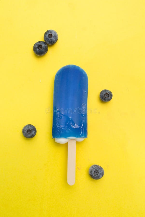 Blueberry popsicle with fresh blueberry on a yellow background. Blueberry popsicle with fresh blueberry on a yellow background