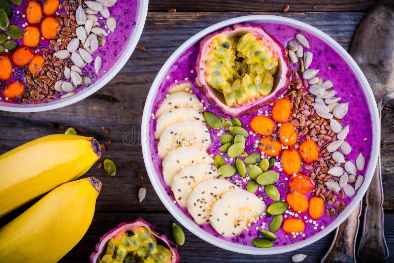 Blueberry smoothies bowl with sea-buckthorn, banana, passion fruit, chia seeds, pumpkin seeds, sunflower and flax seeds