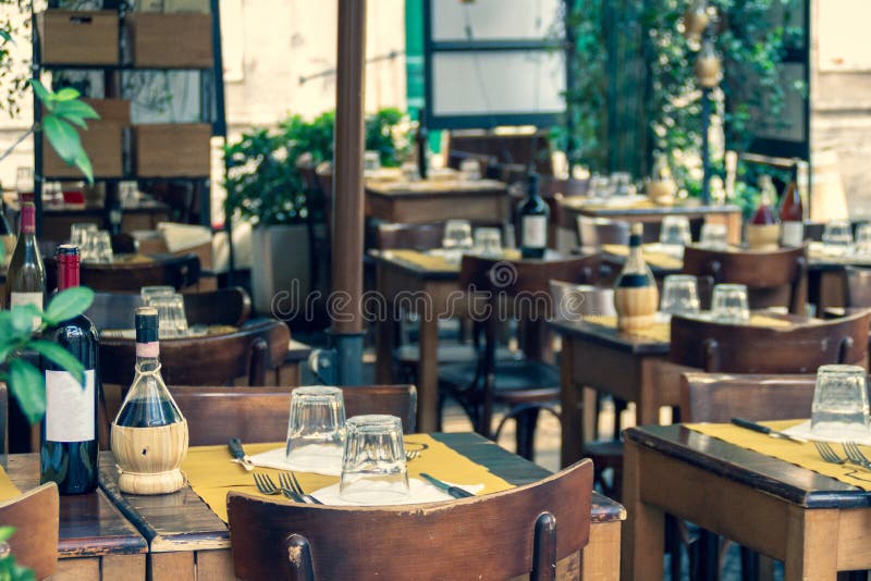 Bluredachtergrond van comfortabel Italiaans openluchtrestaurantterras met gediende houten lijsten en stoelen stock foto Bluredachtergrond van comfortabel Italiaans openluchtrestaurantterras met gediende houten lijsten en stoelen stock foto