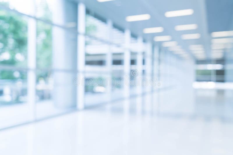 Blurred abstract background interior view looking out toward to empty office lobby and entrance doors and glass curtain wall with frame - blue white balance processing style