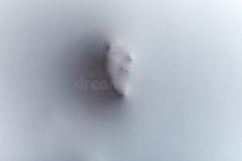 Blurred on black and white head shot of a man with wide open mouth, trying to bite something. copy space. guy making faces behind the cloth