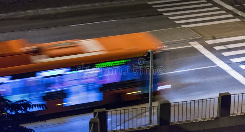 Rozmazaný autobus sa pohybuje po ulici v noci