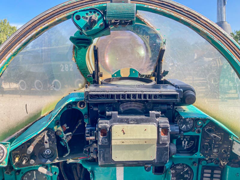 A blurred close-up of an aircraft cockpit with a dome-shaped canopy, various instruments, and a perspective suggesting stock images