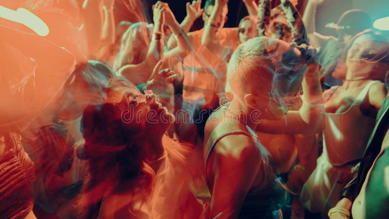 Blurred image of dancing crowd at a vibrant, colorful nightclub party, in a dimly lit, smoke-filled club with vibrant red and royalty free stock image