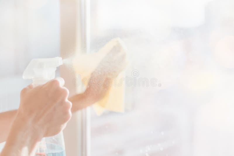 Blurred image of hands with napkin cleaning window.  Woman hands washing the glass on the windows at home with spray.