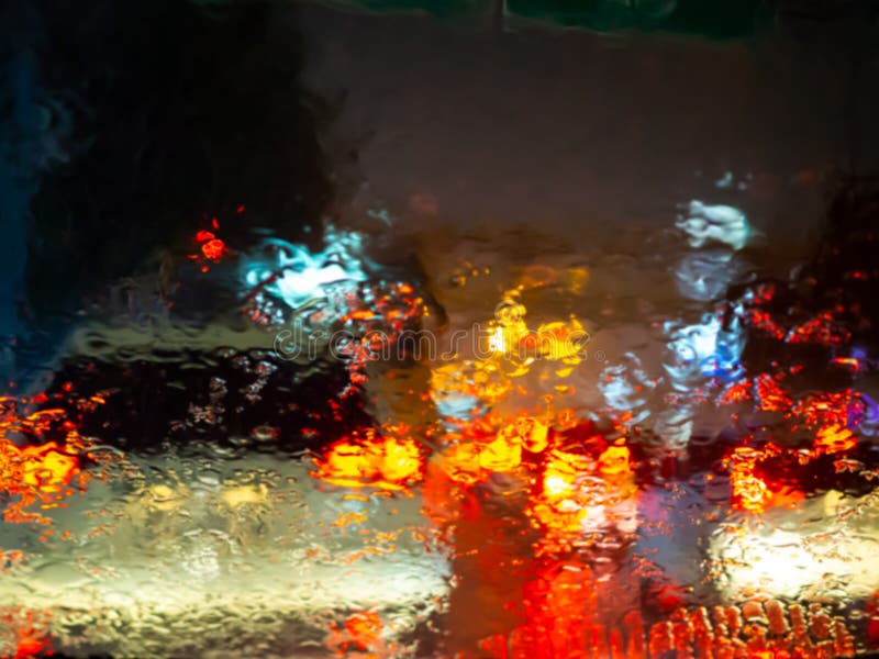 Blurred Rain Drops On Car Window With Road Light Bokeh On Rainy Season