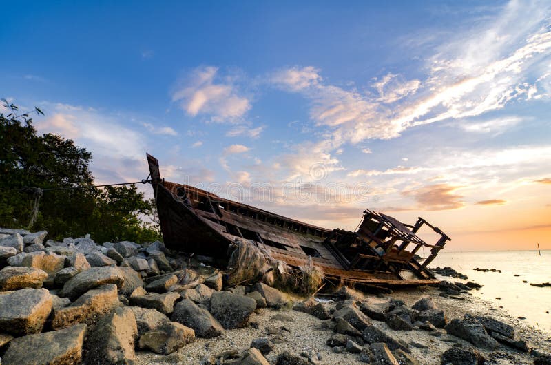 Silhouette image of abandon shipwrecked on rocky shoreline. dark cloud and soft on water