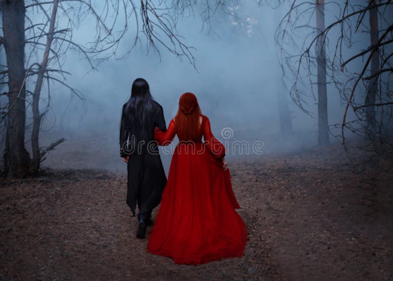 Blurred silhouette of a Gothic couple. Two people walks in the blue fog. A vampire man in a black tailcoat with long
