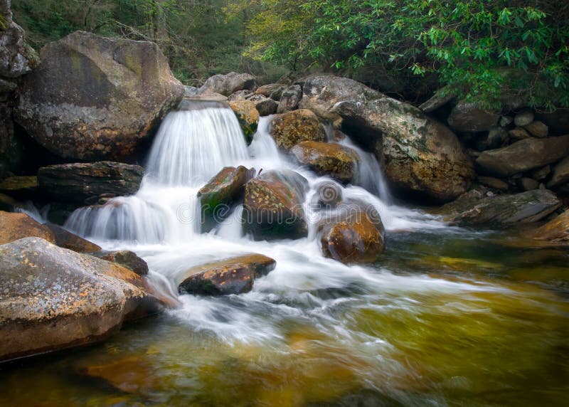 Movimienot difuminar cascadas naturaleza en azul peine montanas verde árboles, oxidado naranja rocas a Agua.