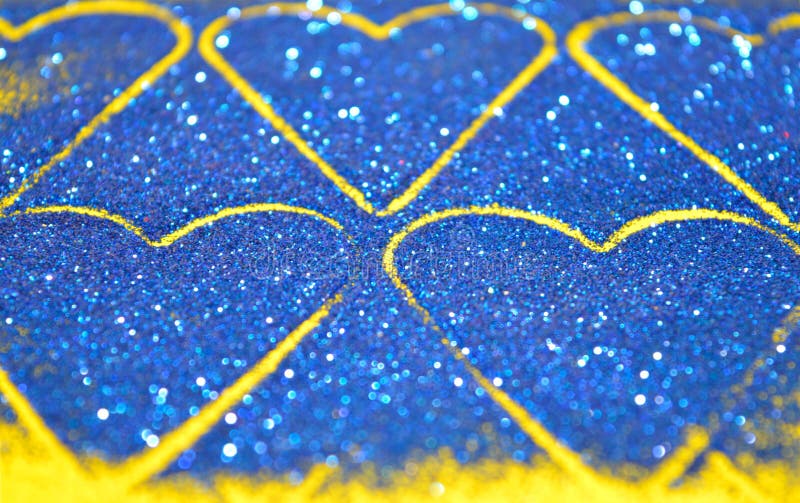 Blurry Abstract Background With Hearts Of Blue Glitter Sparkle On Yellow Surface Stock Photo